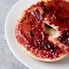 A bagel with jam on it sits on a white Reserve by Libbey porcelain plate.
