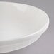 A Libbey ivory porcelain shallow pasta bowl with a rim on a gray surface.