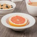 A Libbey Ivory porcelain grapefruit bowl filled with oatmeal and blueberries on a white surface.
