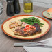 A Libbey mustard yellow stoneware plate with steak, potatoes, and green beans on a table.