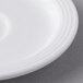 A close-up of a white Aluma porcelain tea saucer with a rim.