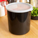 A black container with a white lid.