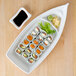 A Thunder Group Blue Bamboo sushi boat filled with sushi on a wooden surface.