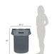 A woman standing next to a Continental Huskee grey plastic trash can.