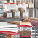 A woman using a Metro Gray Plastic Label Holder to label a container on a shelf.
