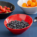 A red slanted catering bowl filled with blueberries, oranges, and strawberries.