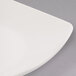 A close-up of a Libbey ivory porcelain coupe plate with a curved edge.