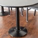 A Lancaster Table & Seating cast iron table base supporting a black table in a restaurant dining area.