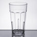 A clear Cambro plastic tumbler with a black rim on a table.