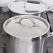 Two Vollrath stainless steel domed covers on pots on a stove.