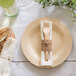 A plate with a Bambu Veneerware bamboo fork and knife wrapped in a white napkin.