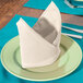 A folded ivory Intedge cloth napkin on a plate with silverware.