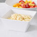 An American Metalcraft square melamine bowl filled with macaroni and cheese and fruit.