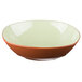A close up of a Libbey terracotta bowl with a white rim and green and orange interior.