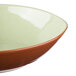 A close up of a Libbey terracotta bowl with a green and brown rim.