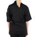 A woman wearing a black Mercer Culinary Millennia Air chef jacket with a full mesh back.