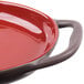 A red stoneware oval baker with a handle.