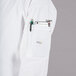A person wearing a Mercer Culinary white long sleeve cook jacket with a pen and phone in the pocket.