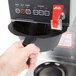 A hand holding a black Bloomfield coffee maker with red touchpad buttons.