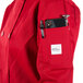 A person wearing a Mercer Culinary Millennia red chef jacket with a phone and pen in the pocket.
