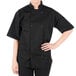 A person wearing a Mercer Culinary black chef coat.