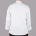 A person wearing a Mercer Culinary white long sleeve chef jacket with cloth knot buttons.