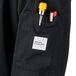 A black Mercer Culinary Millennia Air cook jacket with a pocket containing a pen and a yellow pen.