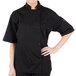 A woman wearing a black Mercer Culinary chef coat with a full mesh back.