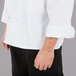 A man wearing a white Mercer Culinary Millennia long sleeve chef jacket with cloth knot buttons.