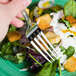 A Bon Chef stainless steel dinner fork on a green salad with croutons.