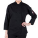 A woman wearing a Mercer Culinary Millennia black long sleeve chef's coat.
