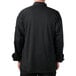 The back of a person wearing a black Mercer Culinary Millennia Air cook jacket with full mesh back.