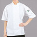 A woman wearing a white Mercer Culinary chef jacket with a mesh back.