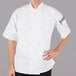 A man wearing a white Mercer Culinary short sleeve chef jacket.