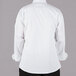 The back of a person wearing a Mercer Culinary Millennia long sleeve white cook jacket with black buttons.