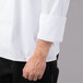 A man wearing a Mercer Culinary Millennia Air white chef coat with a full mesh back.