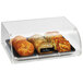 A Vollrath acrylic pastry display case filled with bread on a table.