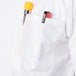 The pocket of a white Mercer Culinary Millennia cook shirt with a pen and a yellow object in it.