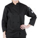 A woman wearing a black Mercer Culinary Millennia chef coat with long sleeves and cloth knot buttons.