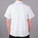 A man wearing a Mercer Culinary Millennia white cook shirt with full mesh back.