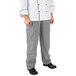 A person wearing Mercer Culinary houndstooth chef pants and a white chef's coat.