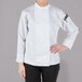 A woman wearing a white Mercer Culinary Millennia long sleeve chef jacket.