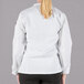 A woman wearing a white Mercer Culinary long sleeve chef jacket with customizable sleeves.