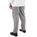 A person wearing Mercer Culinary women's houndstooth chef pants with their hands in their pockets.