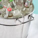 A hammered metal beverage tub filled with bottles of water on a table in a cocktail bar.