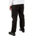 The lower half of a man wearing Mercer Culinary Millennia black chef pants.