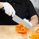 A person using a Mercer Culinary Renaissance chef's knife to cut a bell pepper.