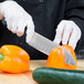 A person cutting a bell pepper with a Mercer Culinary Renaissance Santoku Knife.