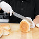 A person using a Mercer Culinary bread knife to cut bread.