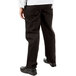 The lower half of a person wearing Mercer Culinary black chef pants.